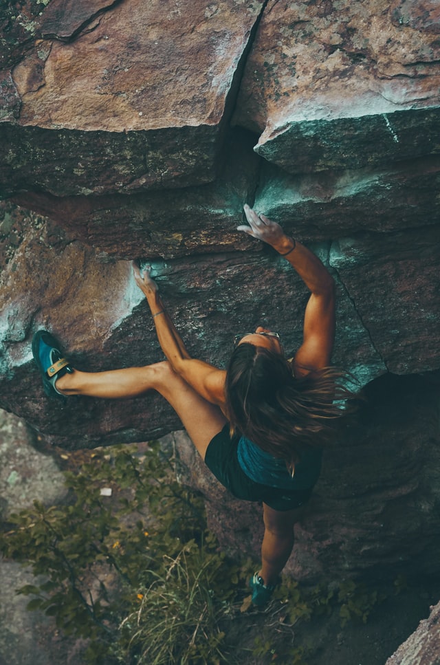 kleine Frau beim Klettern eines Boulders