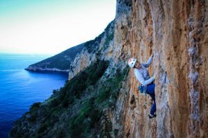 Frau beim Klettern überm Meer