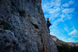 Frau klettert vor blauem Himmel